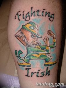 Фото тату ирландского воина с надписью "Fighting Irish". Зеленый костюм, решительный взгляд, динамичная поза. Расположение на руке.