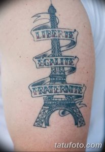 Фото татуировки Эйфелевой башни с надписями 'Liberté, Égalité, Fraternité' на французском языке. Рисунок выполнен в черно-белой гамме с использованием штриховки.