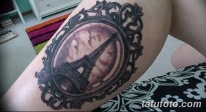 Фото тату Эйфелевой башни в старинной рамке на предплечье. Черно-серый рисунок татуировки с детализированной проработкой и винтажным стилем.