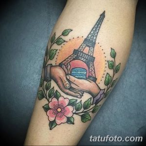 Красочная татуировка на ноге с изображением Эйфелевой башни, сердца и цветов. Цветовая гамма: красный, оранжевый, зеленый.