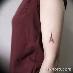 Фотография простой, минималистичной татуировки с изображением Эйфелевой башни, расположенной на внутренней стороне руки девушки.