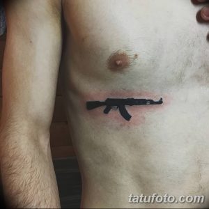 Фото тату черного автомата Калашникова на груди мужчины. Простой, лаконичный рисунок татуировки, выполненный в минималистичном стиле.