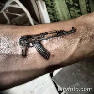 Фото тату небольшого автомата на руке. Черно-серый контурный рисунок татуировки с минималистичным дизайном. Идея для тату для мужчин.