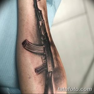 Фото тату реалистичного автомата на предплечье. Черно-серый рисунок татуировки с высокой детализацией и точной передачей формы оружия.