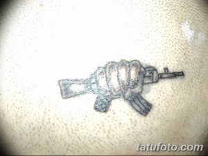 Фото тату небольшого автомата на руке. Черно-серый рисунок татуировки с детальной проработкой механизма оружия. Идея для тату для мужчин.