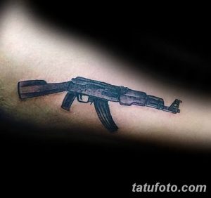 Фото тату черного автомата Калашникова на предплечье. Минималистичный рисунок татуировки, выполненный в технике контура.