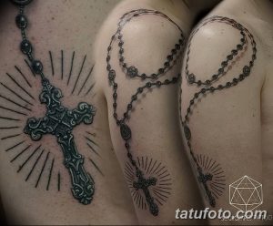 Фото тату: масштабная татуировка четки с крестом, охватывающая плечо и спину. Детализированный рисунок с лучами света, выполненный в черно-серых тонах.