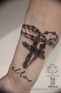Фото тату: стильная черно-белая татуировка четки с крестом и надписью 'Ella' на предплечье. Минималистичный дизайн с акцентом на детали.