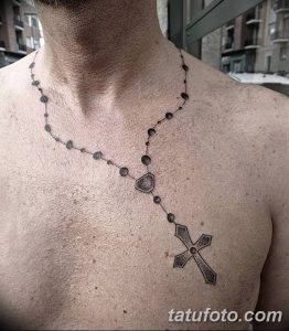 Фото тату на груди: тонкая линия четков с крестом внизу. Минималистичный и элегантный рисунок, символизирующий веру и духовность.