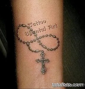 Фото тату четки с крестом и надписью 'Tattoos Spiritual Art' на руке. Рисунок выполнен в черном цвете в минималистичном стиле.