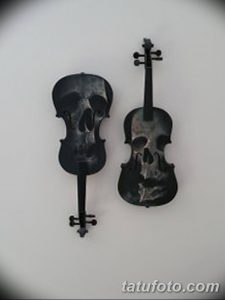 Фото татуировки с изображением двух скрипок, в которых вместо головы скрипки нарисованы черепа. Мрачный, готический стиль, черно-серые тона.