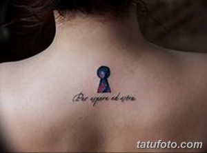 Фотография цветной татуировки на шее, изображающей ключ и надпись на латыни. Тату выполнено в ярких цветах.