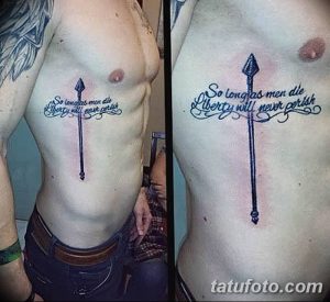 Фото татуировки на боку с изображением копья и цитаты "So long as men die liberty will never perish". Черно-белый стиль, каллиграфический шрифт.