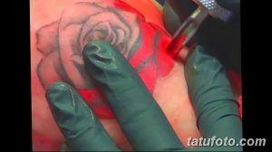 Фото процесса нанесения татуировки розы. Видны руки мастера в перчатках, тату-машинка и контуры рисунка на коже.