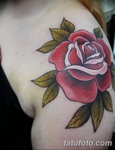 Фото тату: большая красная роза с зелеными листьями на плече. Рисунок татуировки выполнен в традиционном стиле с использованием ярких цветов.