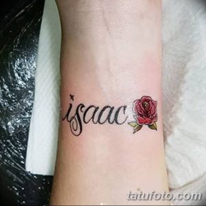 Фото тату: надпись 'Isaac' и маленькая красная роза на запястье, выполненные в тонком и изящном стиле.