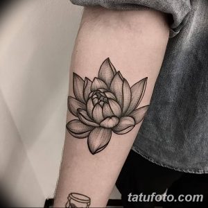 Фото тату: Черно-белый цветок лотоса, выполненный в технике dotwork, расположенный на предплечье. Детализированный рисунок с использованием точек.