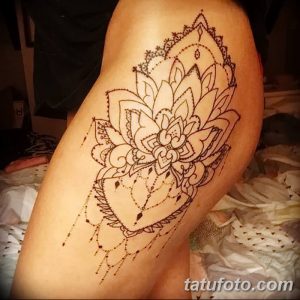 Фото татуировки лотоса на бедре, выполненной в стиле мехенди с использованием тонких линий и узоров, напоминающих хну.