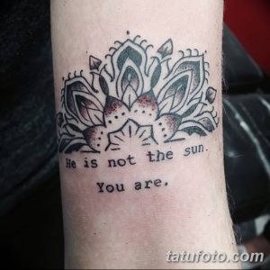 Фото тату: детализированный цветок лотоса в технике blackwork с надписью "He is not the sun. You are." на предплечье.