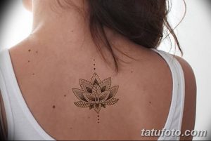 Фото тату: детальный рисунок лотоса в стиле дотворк на женской спине. Эскиз татуировки выполнен в коричневых тонах с тонкими линиями.