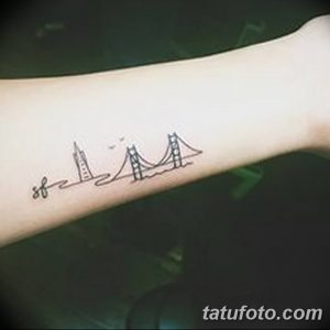 Фото минималистичной татуировки с силуэтами мостов, небоскребов и самолета на предплечье. Рисунок выполнен в технике тонких линий и черного цвета.