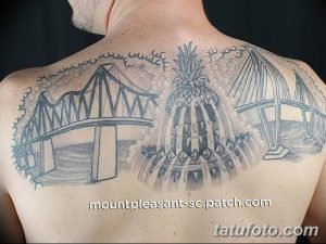 Фото большой татуировки с изображением мостов и ананаса на спине. Рисунок выполнен в технике черного цвета и штриховки.