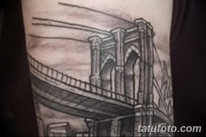 Фото эскиза татуировки Бруклинского моста, выполненного в серо-черной гамме. Изображение фокусируется на архитектурных элементах моста, с акцентом на его опоры и тросы.
