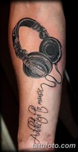 Фото тату: реалистичное изображение наушников с надписью 'Addicted to music' на руке.