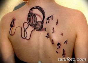 Фото тату наушников и музыкальных нот на спине. Черно-белый рисунок с динамичной композицией.