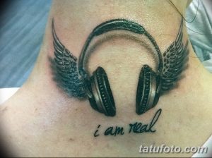Фото тату на шее: наушники с крыльями и надписью 'i am real'. Черно-белый рисунок татуировки с детализированными крыльями.