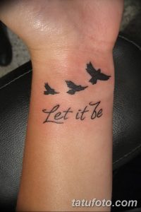 Фото тату на запястье: три силуэта птиц и надпись 'Let it be', выполненные черным цветом в минималистичном стиле.