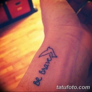 Фото тату: маленькая черная птица и надпись 'Be brave' на руке. Простой и вдохновляющий рисунок татуировки.