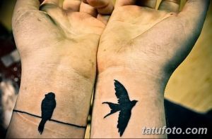 Фото парных тату на запястьях: одна птица сидит на ветке, другая летит, минималистичный дизайн, черные силуэты.