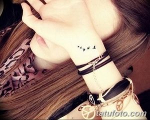 Фото тату с изображением нескольких маленьких черных птиц на запястье девушки. Изящный и минималистичный рисунок татуировки.
