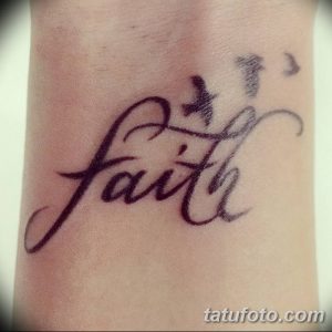 Фото татуировки надписи "Faith" (Вера) с изображением летящей птицы на запястье. Черно-белый рисунок, каллиграфия, религиозный символ.