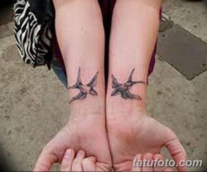 Фото парных татуировок на запястьях с изображением двух ласточек в полете. Детализированный рисунок татуировки, выполненный в черном цвете.
