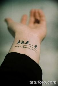 Фото тату с изображением четырех маленьких черных птиц и надписи "you me we" на запястье. Минималистичный и романтичный рисунок татуировки.