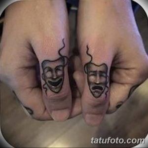 Фото мини-татуировок на пальцах: две маленькие маски - смеющаяся и плачущая. Стиль - минимализм, черно-белое исполнение.