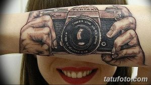 Фото тату на руке: реалистичное изображение рук, держащих фотоаппарат Pentax, выполненное в черно-серых тонах.
