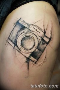 Фото тату: эскиз фотоаппарата, выполненный в стиле скетча, с использованием тонких линий и штриховки. Черно-белая татуировка на руке.