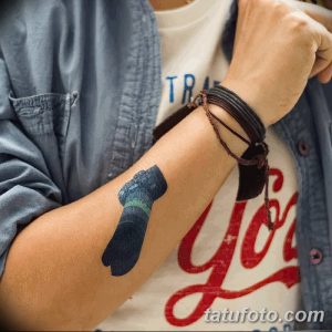 Простая татуировка в виде носка и надписи 'You', выполненная в красно-синей гамме. Минималистичный дизайн на руке.