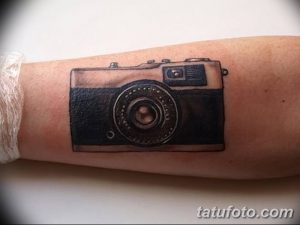 Фото татуировки с изображением старинной камеры на руке. Черно-серый рисунок, детализированная проработка оптики и корпуса.