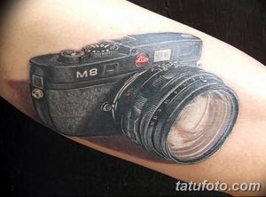 Черно-белое фото реалистичной татуировки камеры Leica M8 на предплечье. Детализированный рисунок, точная передача формы и текстуры.