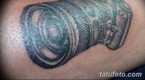 Простая черно-серая татуировка объектива камеры на руке. Минималистичный рисунок с четкими линиями и детальной проработкой.