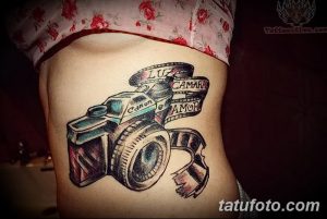 Фото тату фотоаппарата Canon с размотанной кинопленкой и надписью 'LUZ CAMARA AMOR'. Винтажный и романтичный рисунок татуировки на боку.
