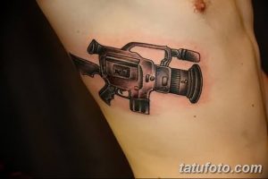 Фото тату видеокамеры на руке. Детализированный рисунок татуировки в черно-серых тонах, символизирующий кинематограф и творчество.