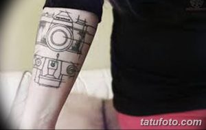 Фото тату схематичного изображения фотоаппарата на руке. Черно-белый рисунок татуировки в стиле графики.