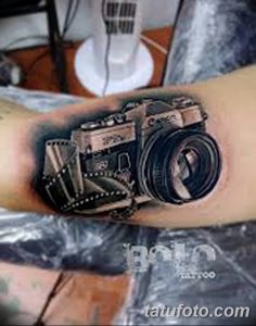 Фото тату реалистичного изображения фотоаппарата на руке. Детализированный рисунок татуировки с тенями и бликами.