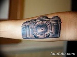 Фото тату на предплечье: реалистичное изображение фотоаппарата Nikon. Черно-серый рисунок татуировки с высокой детализацией.