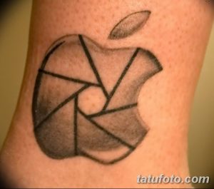 Оригинальное тату на предплечье с изображением логотипа Apple, стилизованного под диафрагму камеры. Черно-серый рисунок.